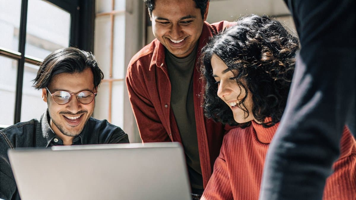 A team collaborating around a laptop